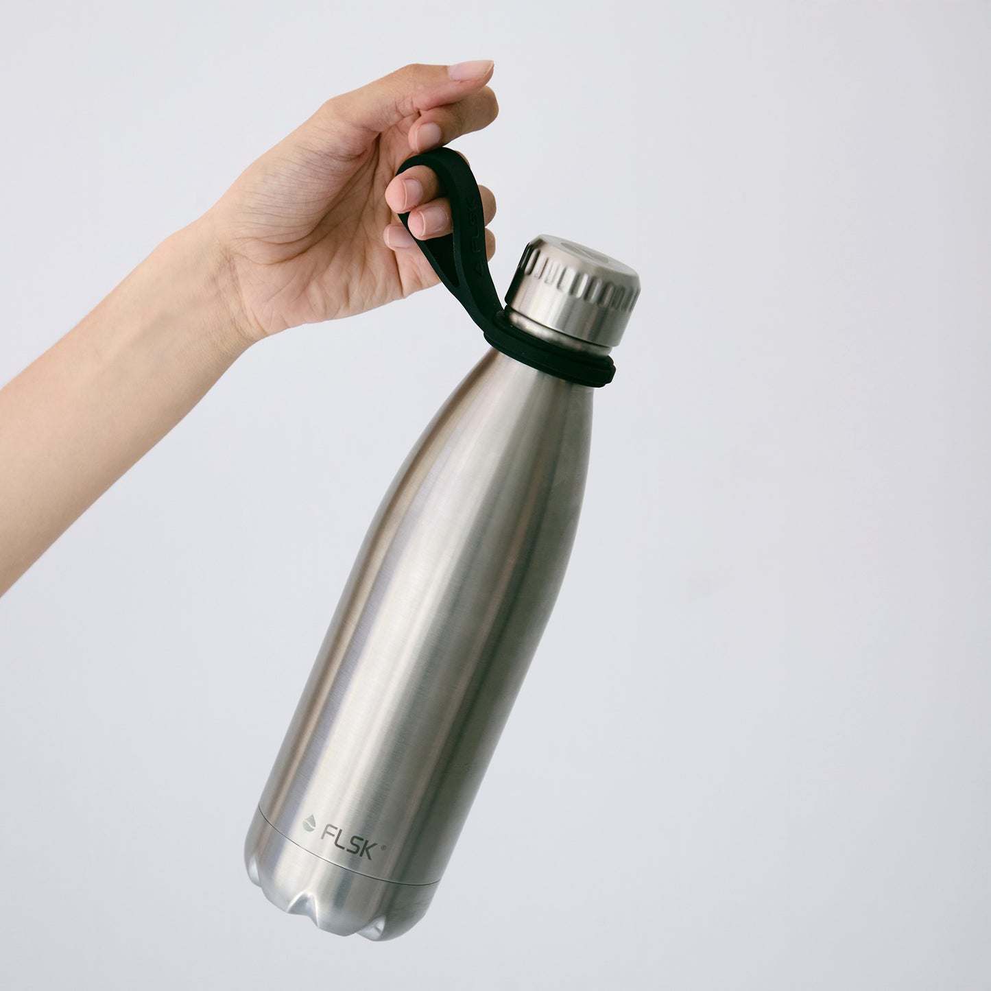 Frauenhand präsentiert FLSK Trinkflasche mit Silikonhalterung